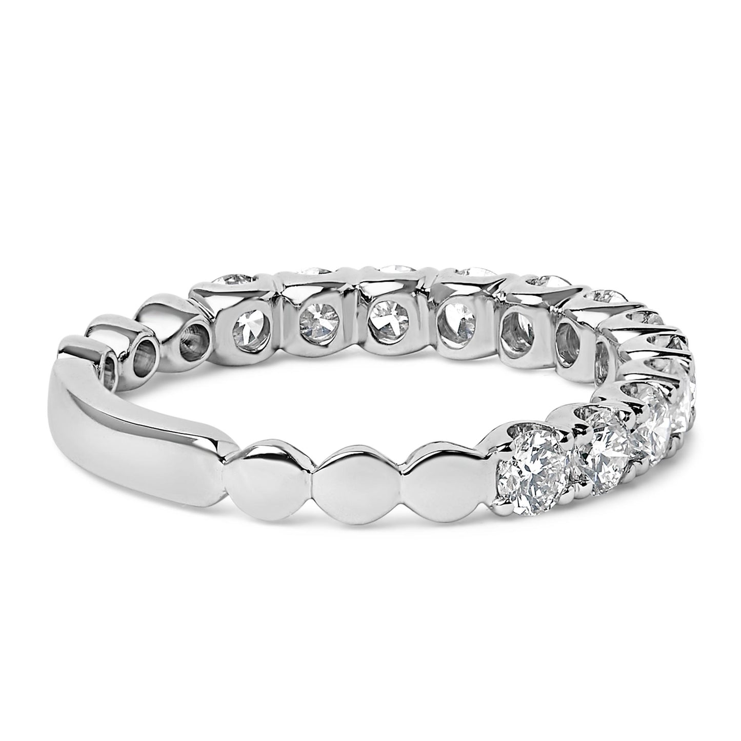 Close-up angled view of a white metal ring featuring multiple round white gemstones in 4-prong settings encircling the band.