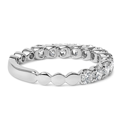 Close-up angled view of a white metal ring featuring multiple round white gemstones in 4-prong settings encircling the band.