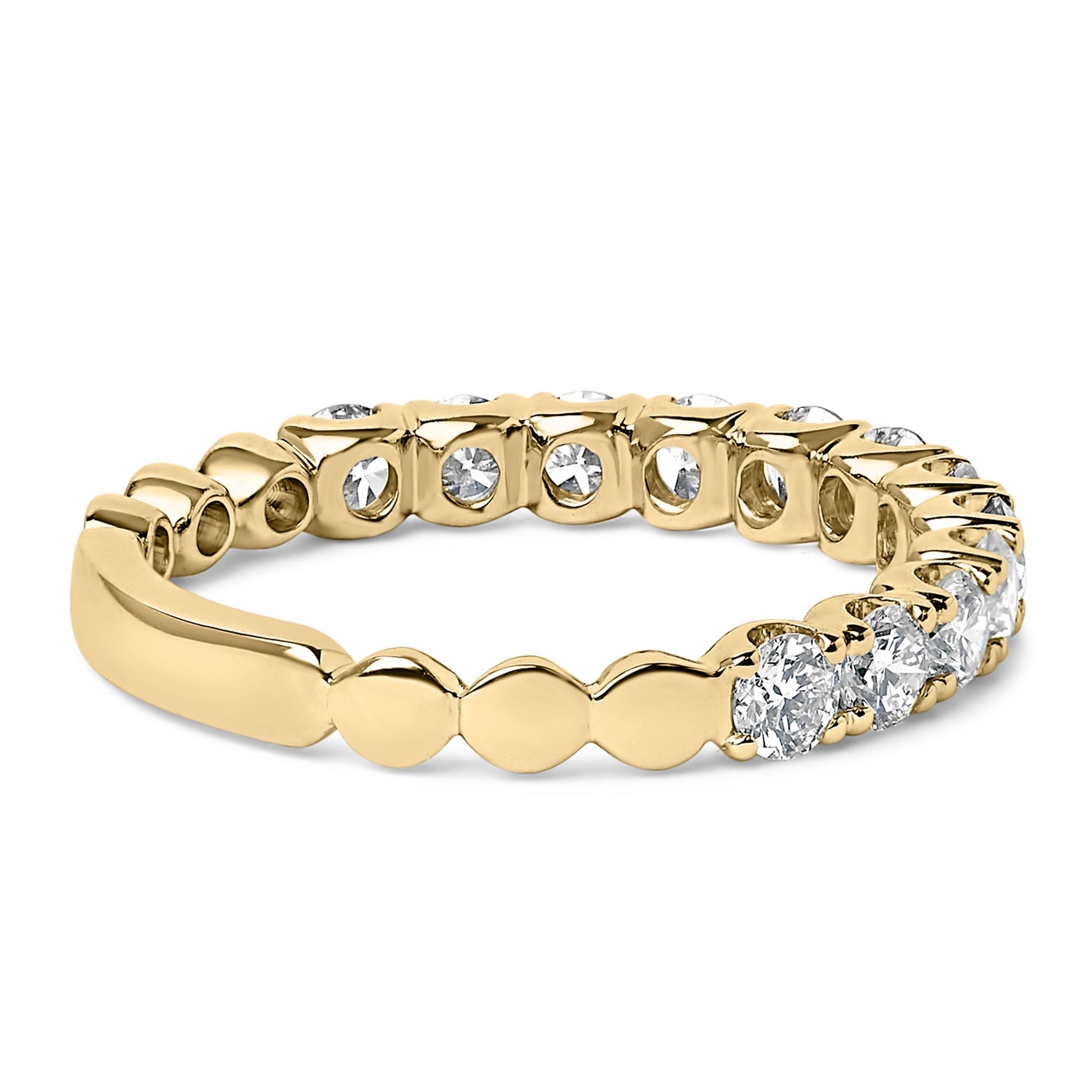 Yellow metal ring with round white gemstones in 4-prong settings around the band, shown in a close-up angled side view.
