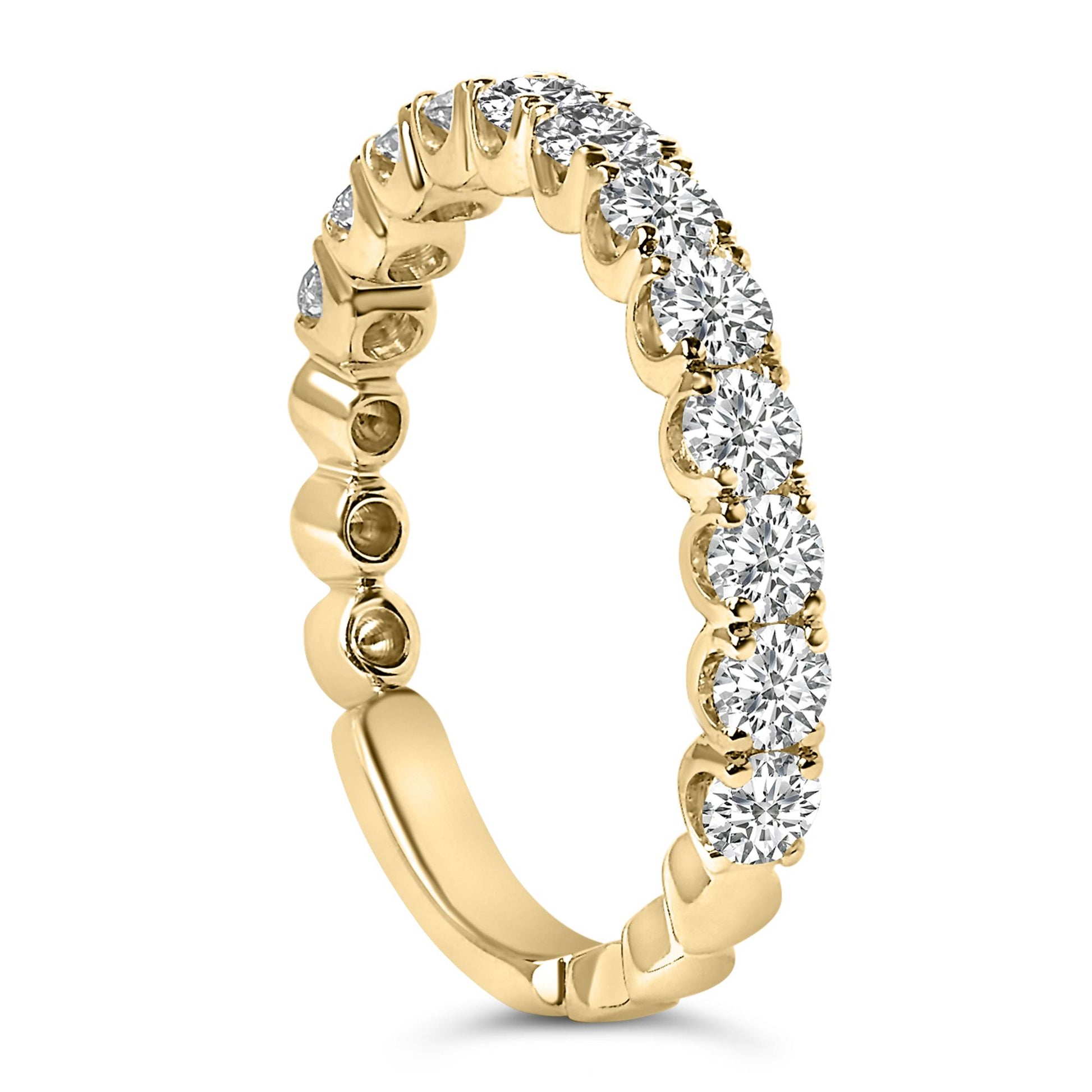 Close-up image of a yellow metal ring with round white gemstones in four-prong settings all around the band, shown at a slight angle.