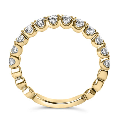 Close-up view of a yellow metal ring with round white gemstones in 4-prong settings all around the band, shown from the side angle.