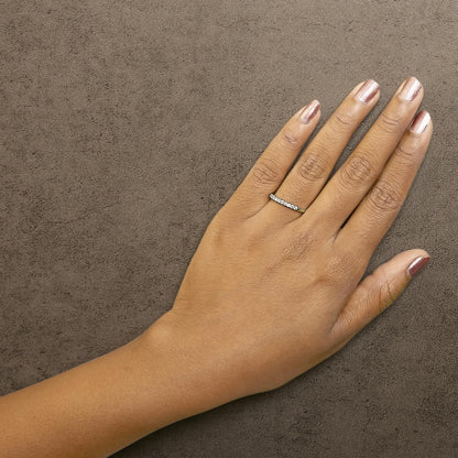 Ring with round white gemstones in prong settings on a yellow band, shown worn on a model's hand, top view.