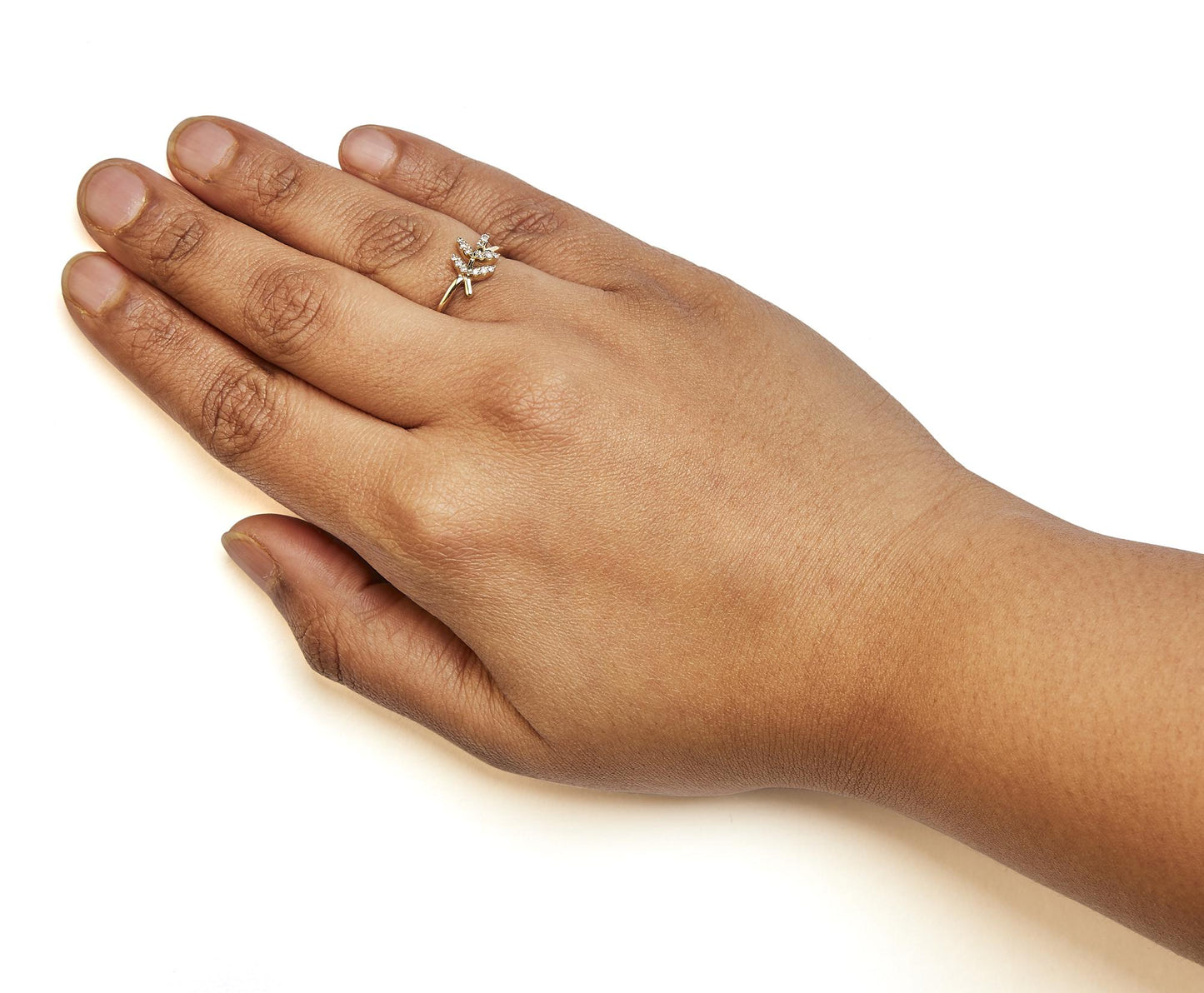 Close-up side angle of a yellow metal ring with two branches of white round pave-set gemstones, worn on a model's hand.
