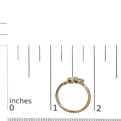 Top-down view of a yellow metal ring with two rows of small white round gemstones in pave settings, placed on a ruler for size reference.