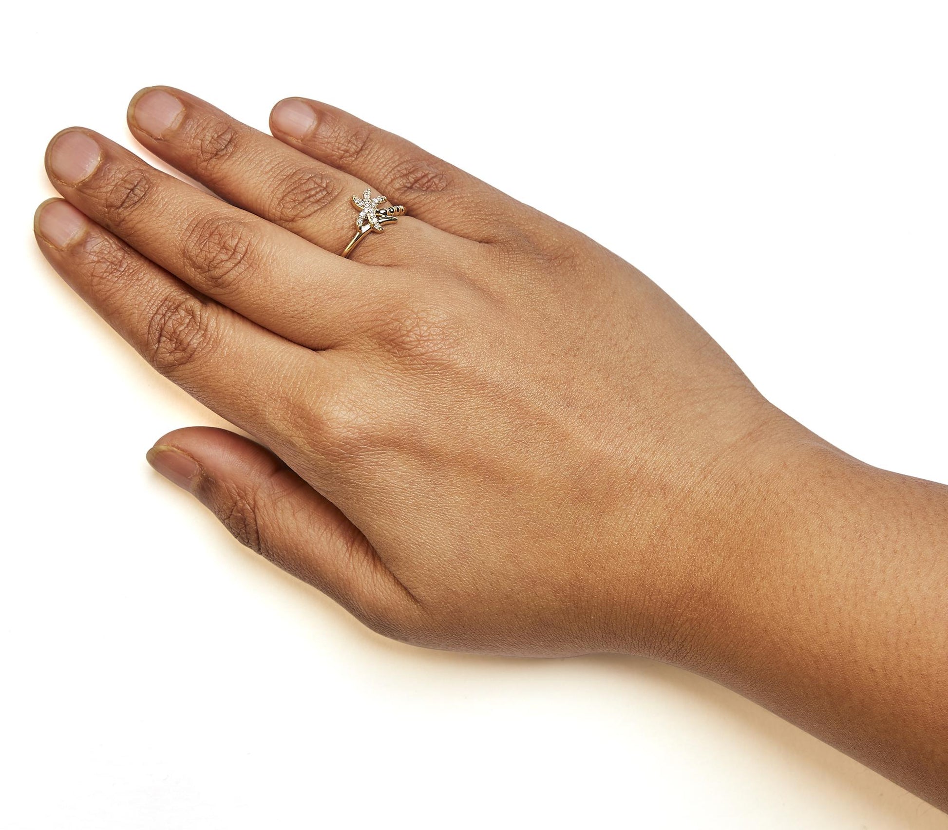 Close-up of a yellow ring with white round pave gemstones, worn on a model's left hand, shot from above.
