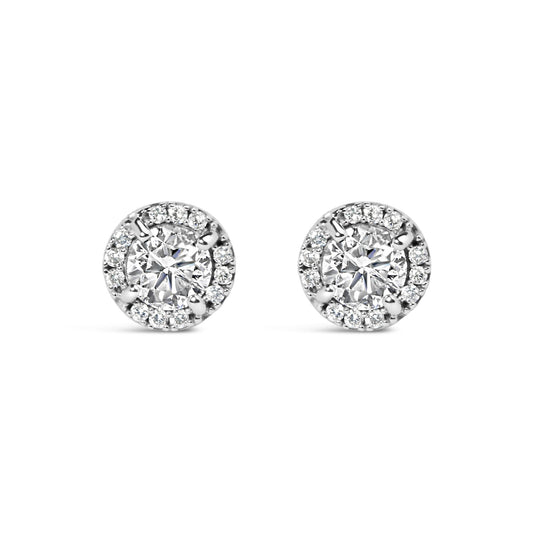 Front view of a pair of white metal stud earrings featuring a central round gemstone in a four-prong setting, surrounded by smaller round gemstones in a shared prong and channel setting.