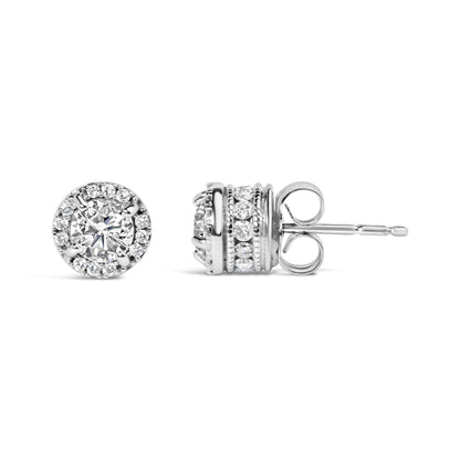 Close-up front and side view of a pair of white metal stud earrings featuring a central round gemstone in a four-prong setting surrounded by a halo of smaller round gemstones with additional rows of round gemstones in shared prong and channel settings on the sides.