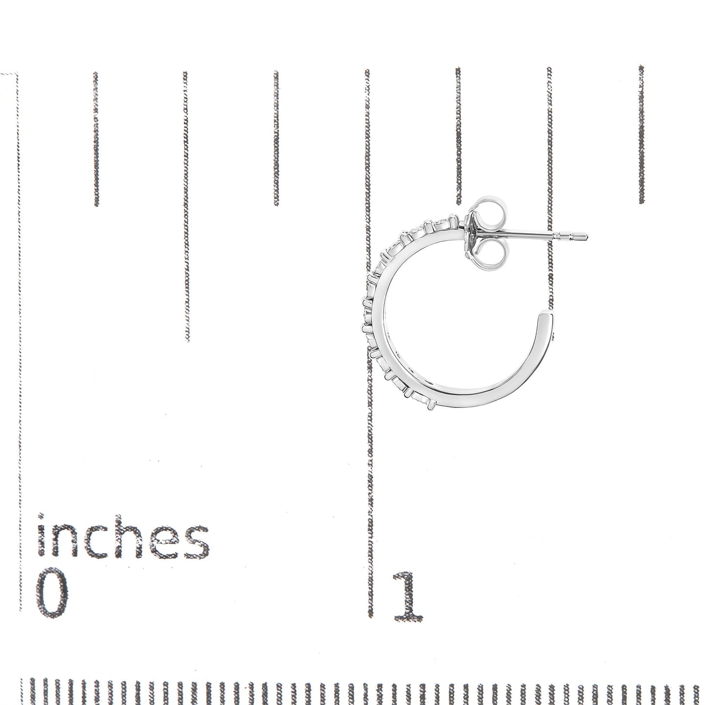 Close-up side view of a white metal hoop earring with round white gemstones in miracle settings, placed on a ruler for size reference.