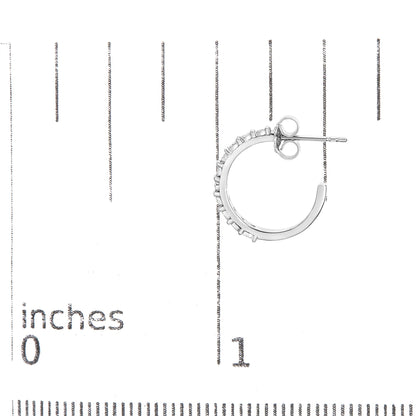 Close-up side view of a white metal hoop earring with round white gemstones in miracle settings, placed on a ruler for size reference.