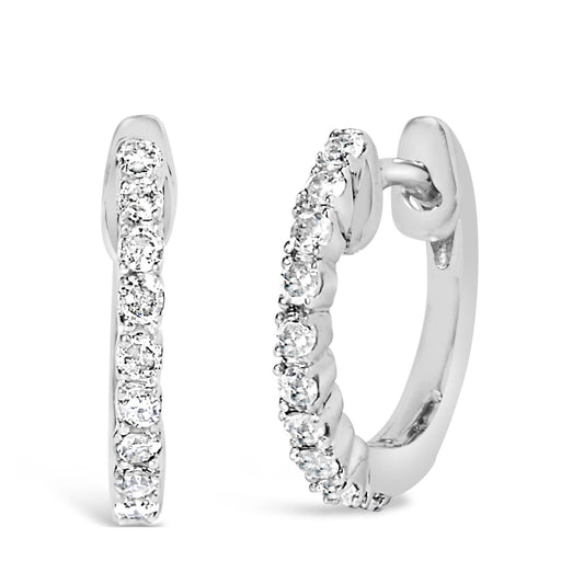 Front and angled side view of a pair of white metal hoop earrings set with round white gemstones in 4-prong settings.