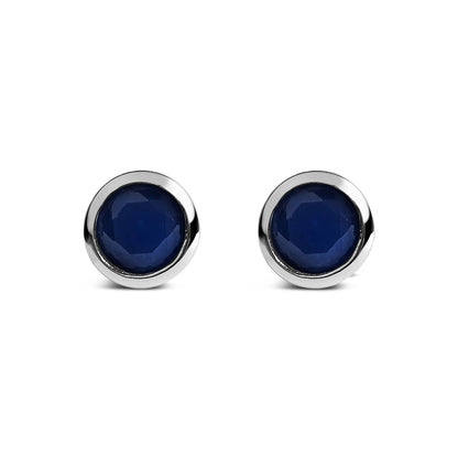 Pair of round blue gemstone stud earrings in a white metal bezel setting, shown from the front on a white background.