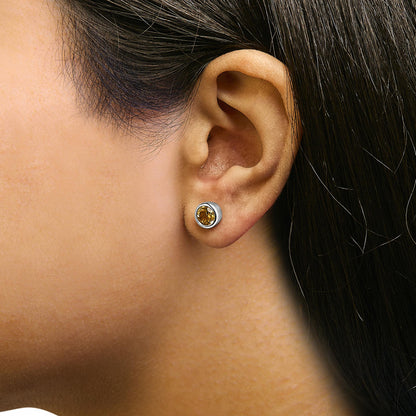 Close-up side view of a model wearing a white metal stud earring with a round yellow gemstone in a bezel setting.