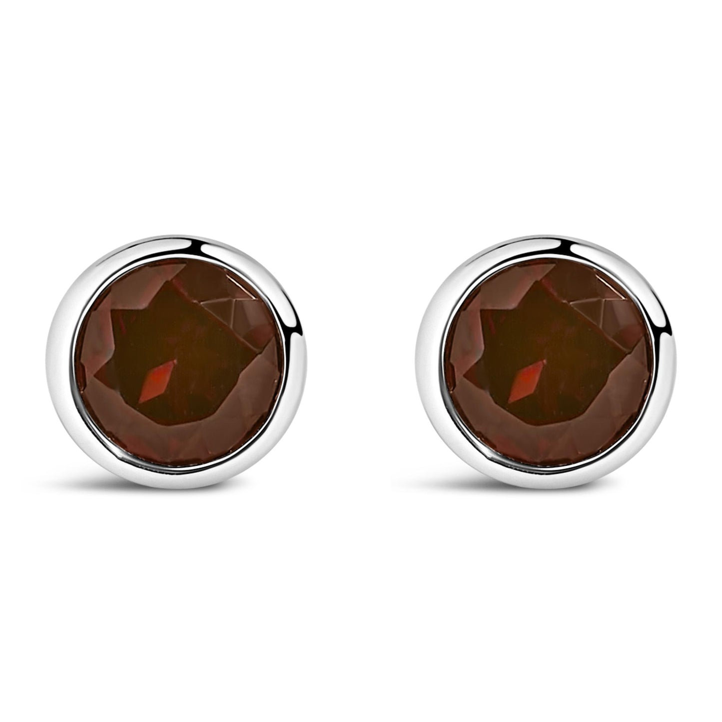 Pair of round white metal bezel-set red gemstone stud earrings shown from the front on a white background.