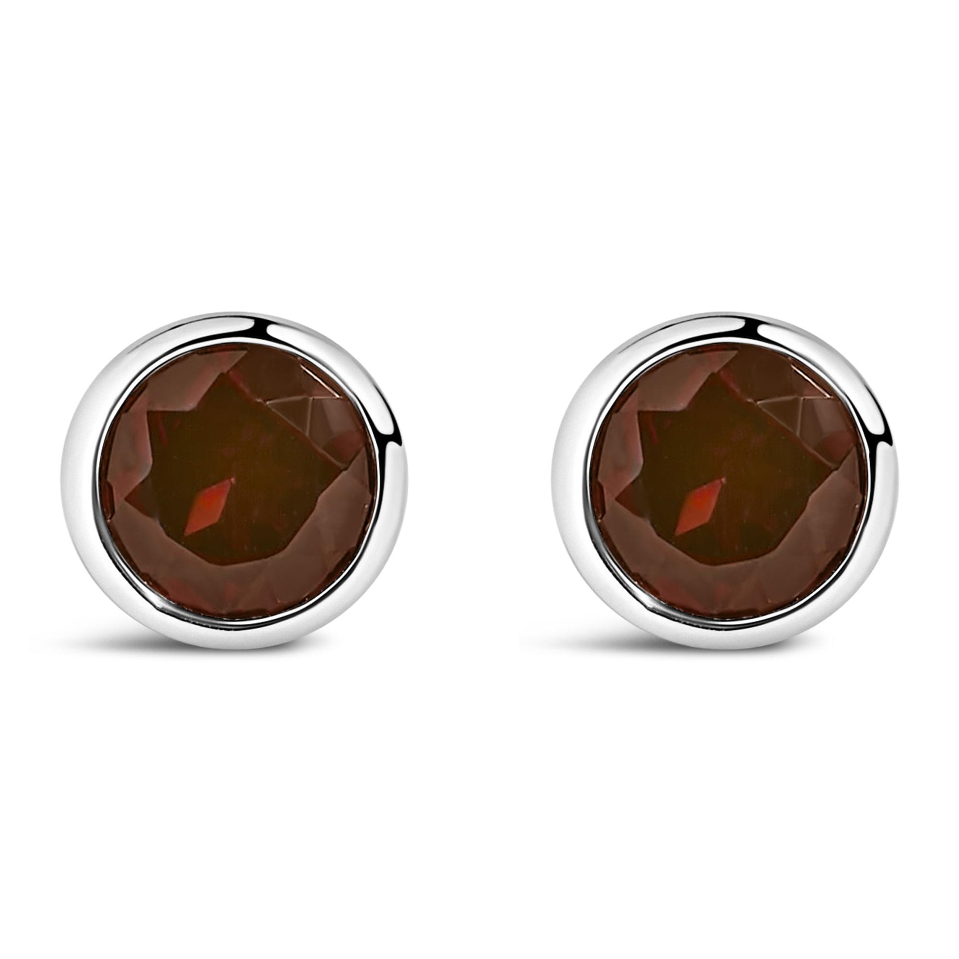 Pair of round white metal bezel-set red gemstone stud earrings shown from the front on a white background.