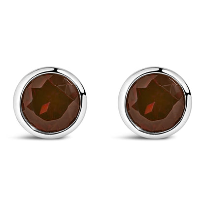 Pair of round white metal bezel-set red gemstone stud earrings shown from the front on a white background.