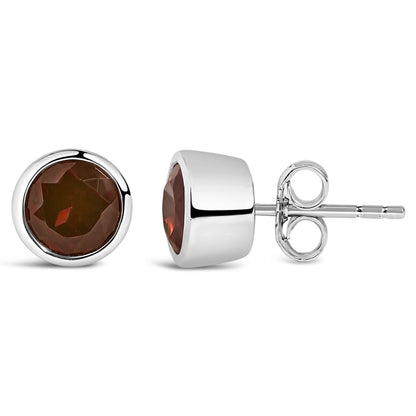 Pair of round white stud earrings with red gemstones in bezel settings, shown from front and side angles on a white background.