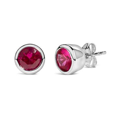 Pair of white metal stud earrings with round red gemstones in bezel settings, shown in a close-up front and side angled shot on a white background.