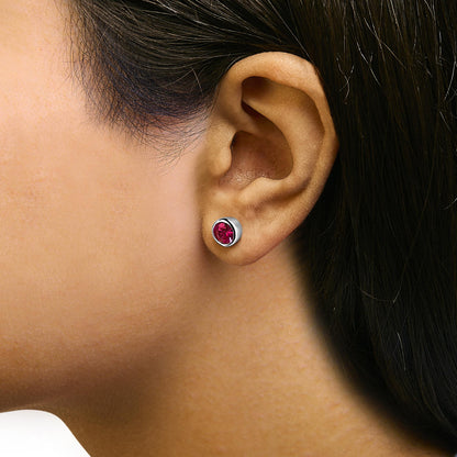Close-up side view of a model wearing a white metal stud earring featuring a round red gemstone in a bezel setting.