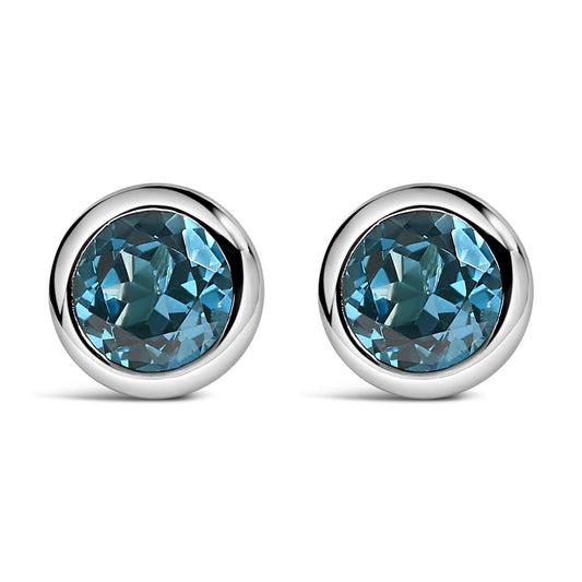 Pair of white metal round bezel-set earrings with round blue gemstones, shown in a front-facing angle.