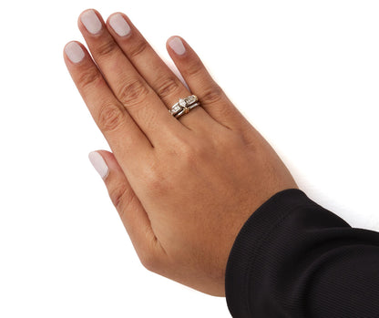 Two-toned ring with a marquise-shaped white gemstone in prong setting and round white gemstones in pave setting, worn on a model's hand, top-down angle.