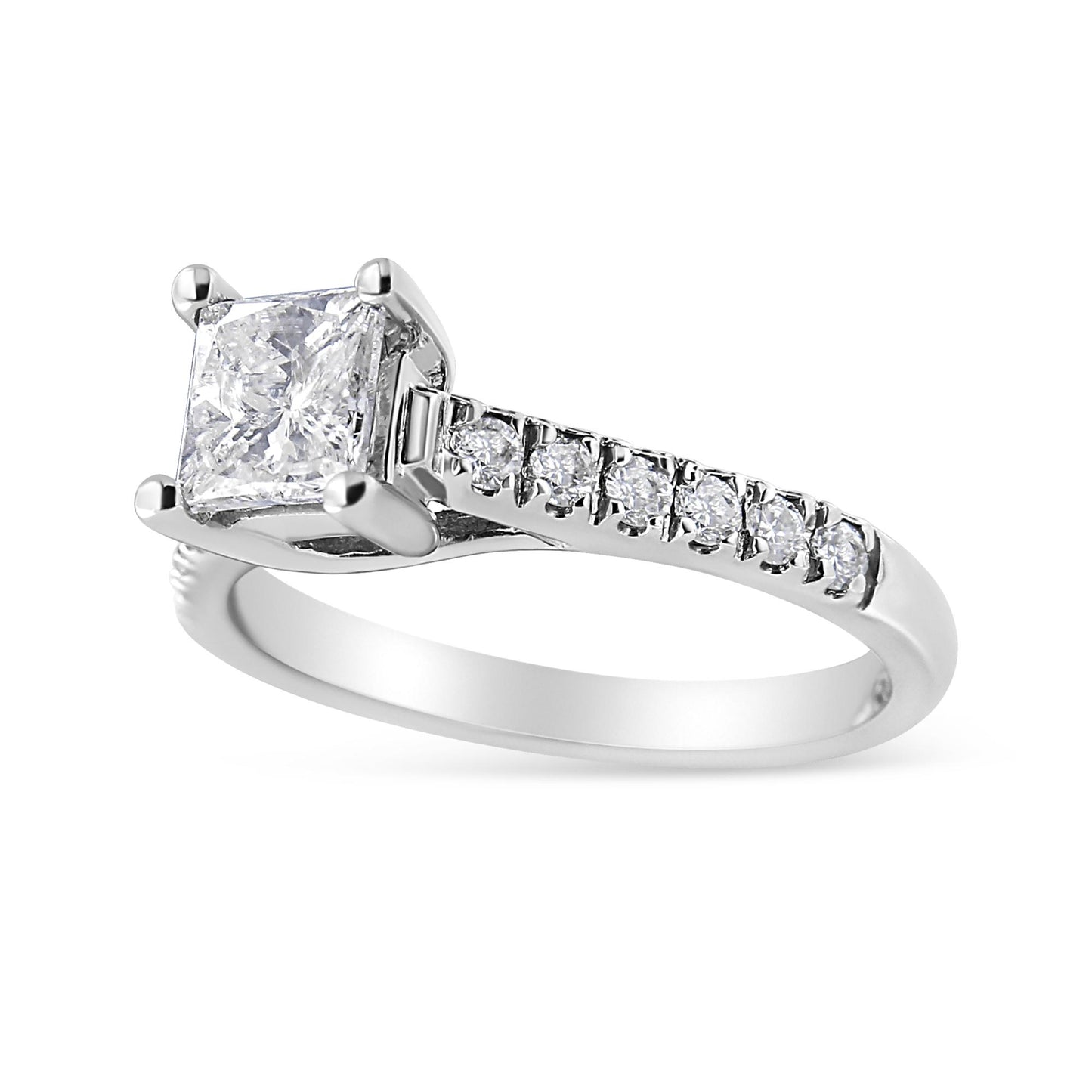 White metal ring with a princess shape white gemstone in a four-prong setting, accompanied by round white gemstones set along the band, shown in a close-up angled view.