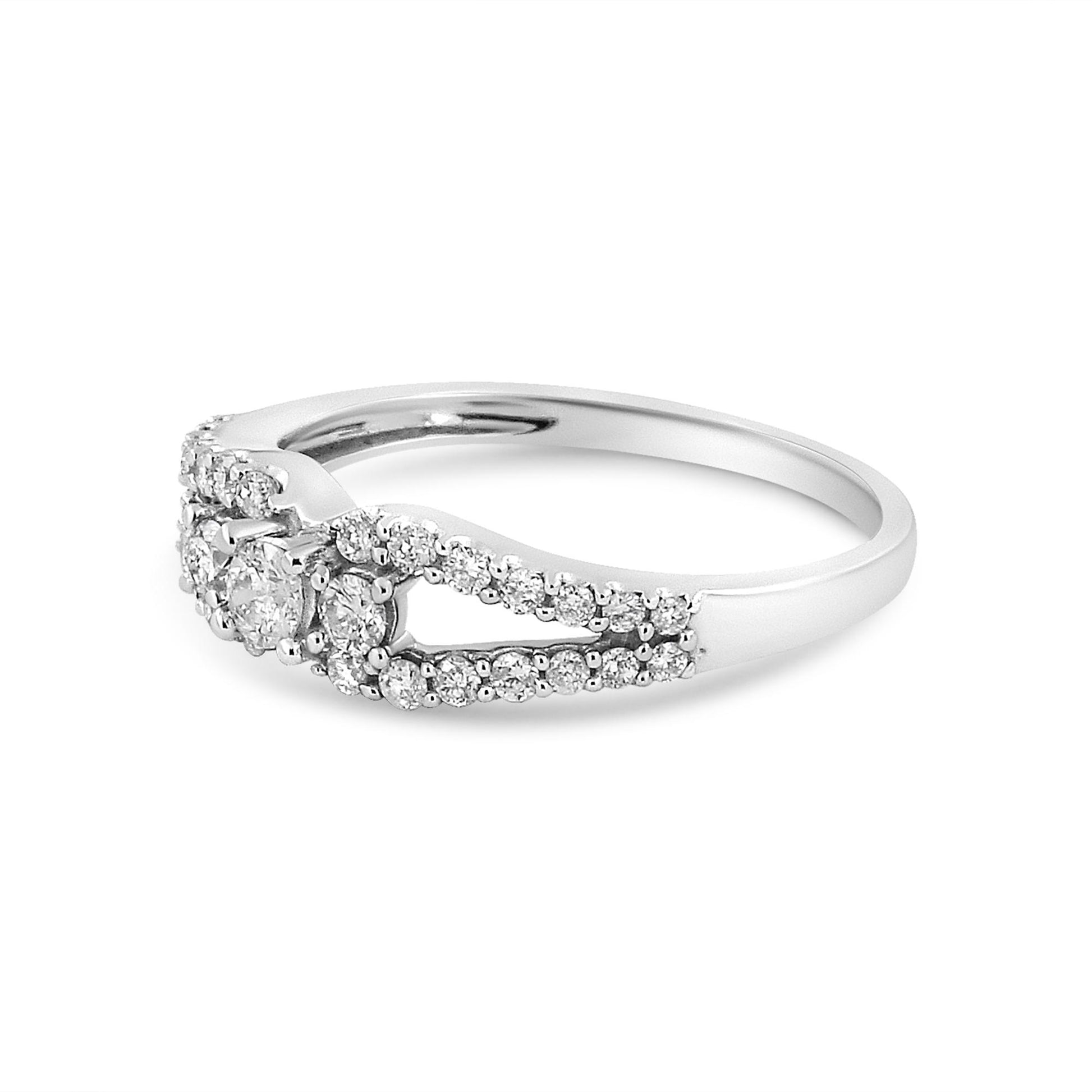Side angle view of a white metal ring featuring multiple round white gemstones in prong settings along the band and clustered at the center.