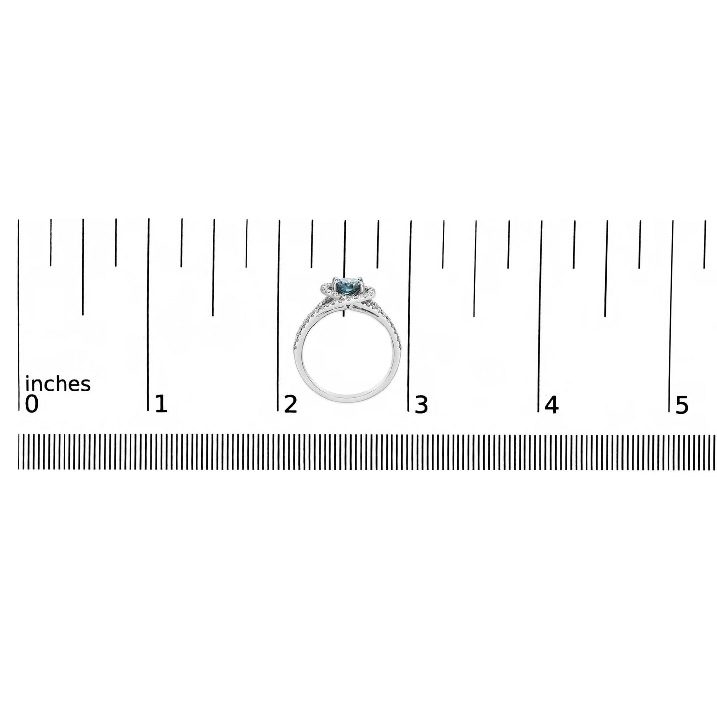 Top-down view of a white metal ring with a central blue round gemstone in prong setting and multiple small white round gemstones in prong settings along the band, placed on a ruler for size reference.