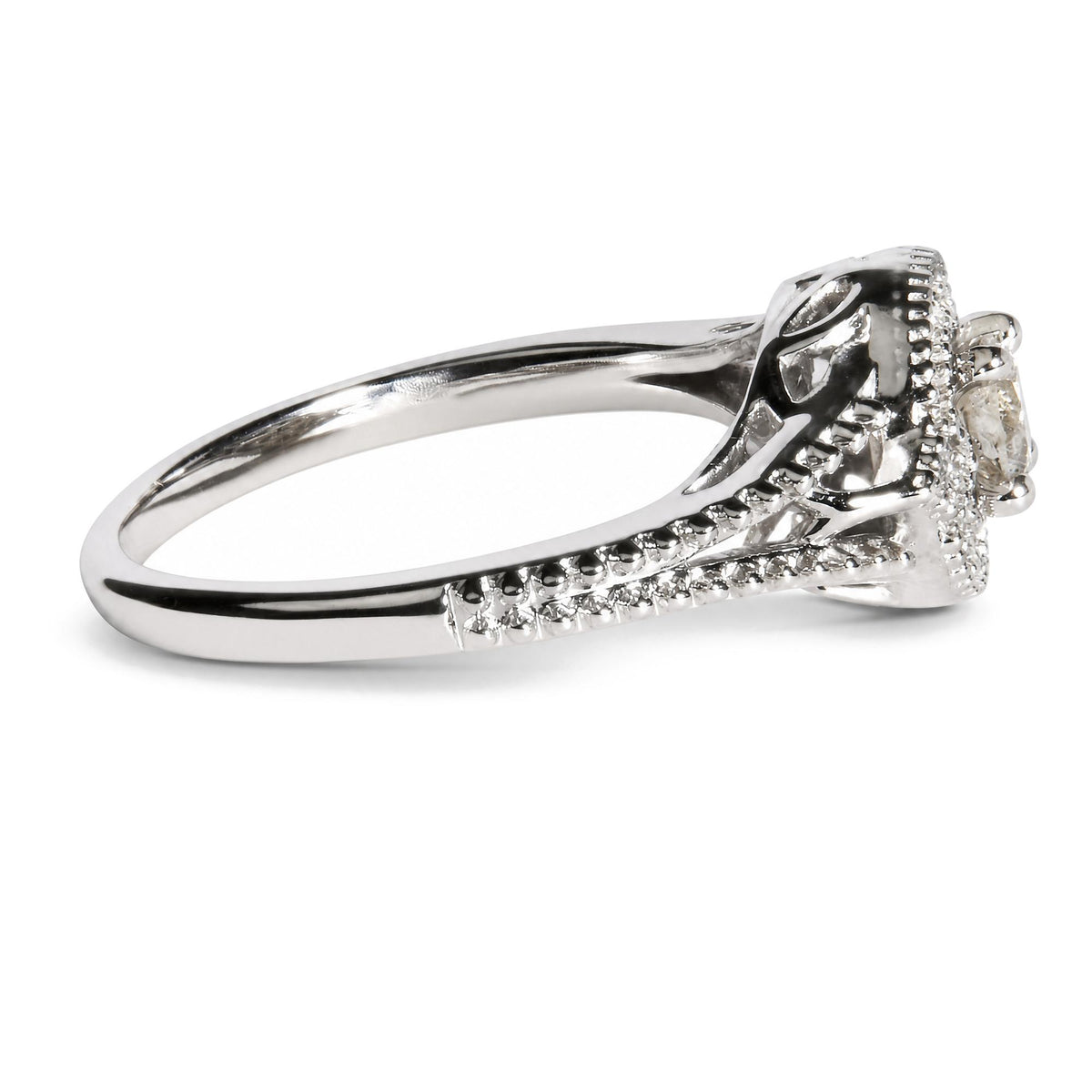 Close-up side angle of a white metal ring featuring one prominent round white gemstone in a prong setting, with additional smaller round white gemstones set along the band.