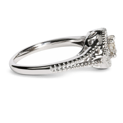 Close-up side angle of a white metal ring featuring one prominent round white gemstone in a prong setting, with additional smaller round white gemstones set along the band.