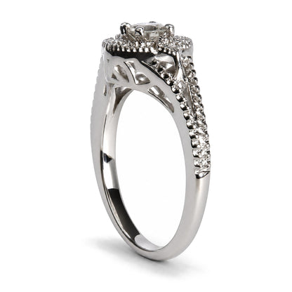 Close-up side angle of a white metal ring with one larger round white gemstone in a prong setting at the top, surrounded and accented by multiple smaller round white gemstones in prong settings along the band.