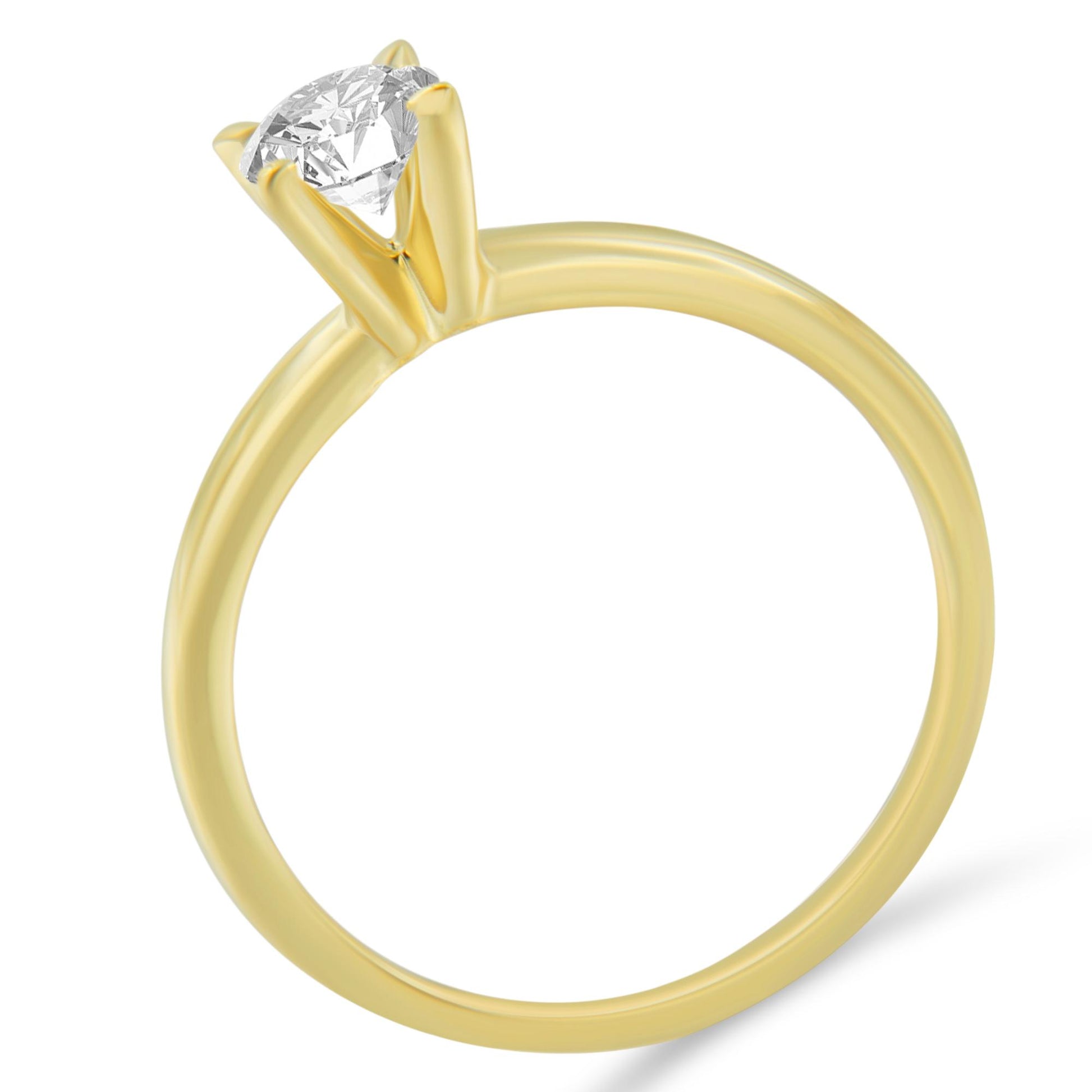 Yellow metal ring with a single round white gemstone in a prong setting, shown from a side angle.