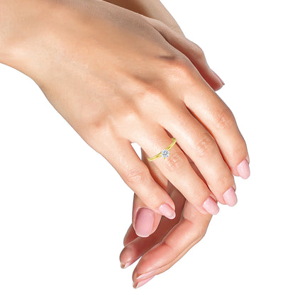 Close-up front angle of a yellow ring with a round white gemstone in a prong setting, worn on a model's hand.