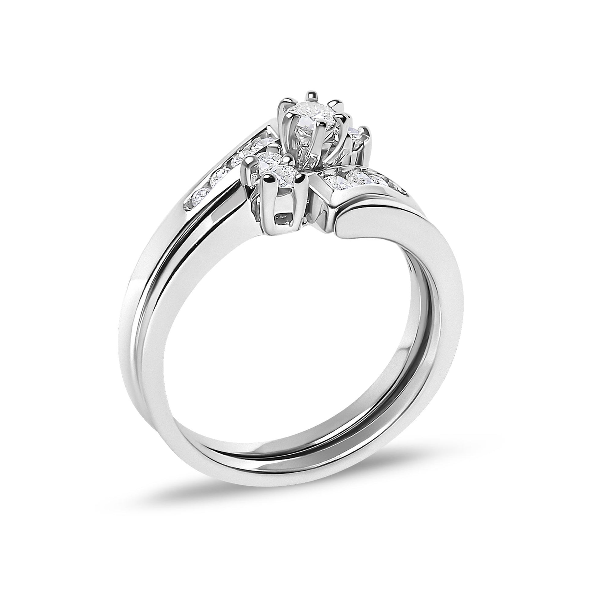 Close-up angled view of a white metal ring featuring a central round white gemstone in a prong setting, flanked by smaller round white gemstones set into the band.