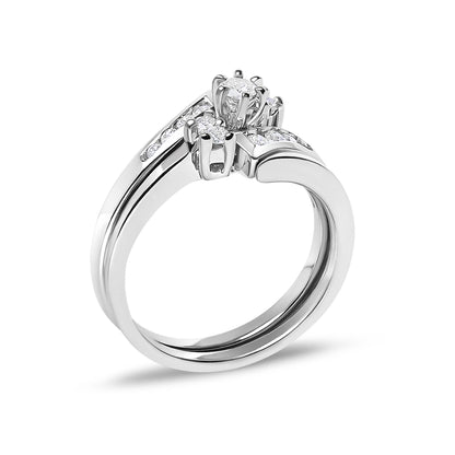 Close-up angled view of a white metal ring featuring a central round white gemstone in a prong setting, flanked by smaller round white gemstones set into the band.