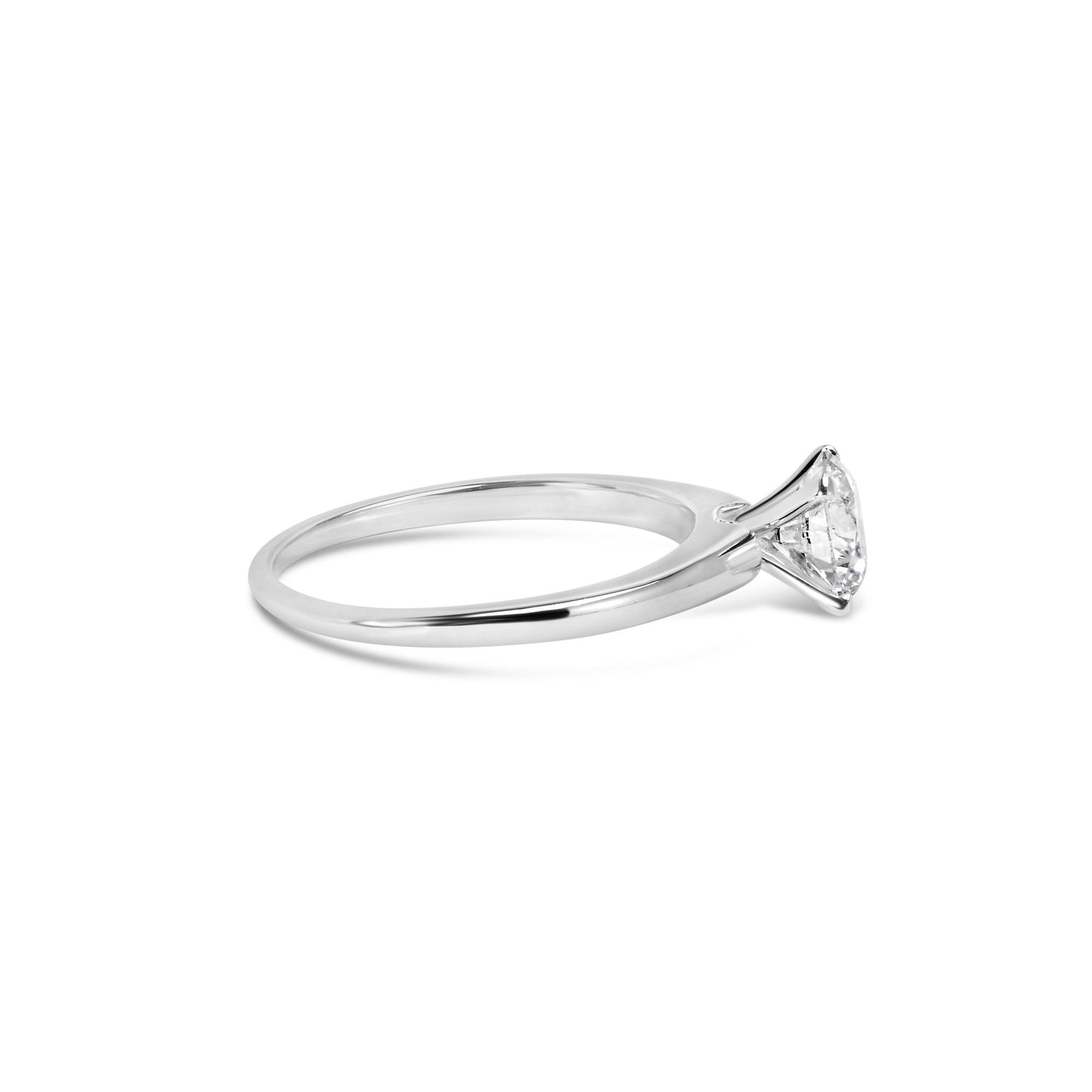 Side angle view of a white metal ring with a round white gemstone in a 4-prong setting.
