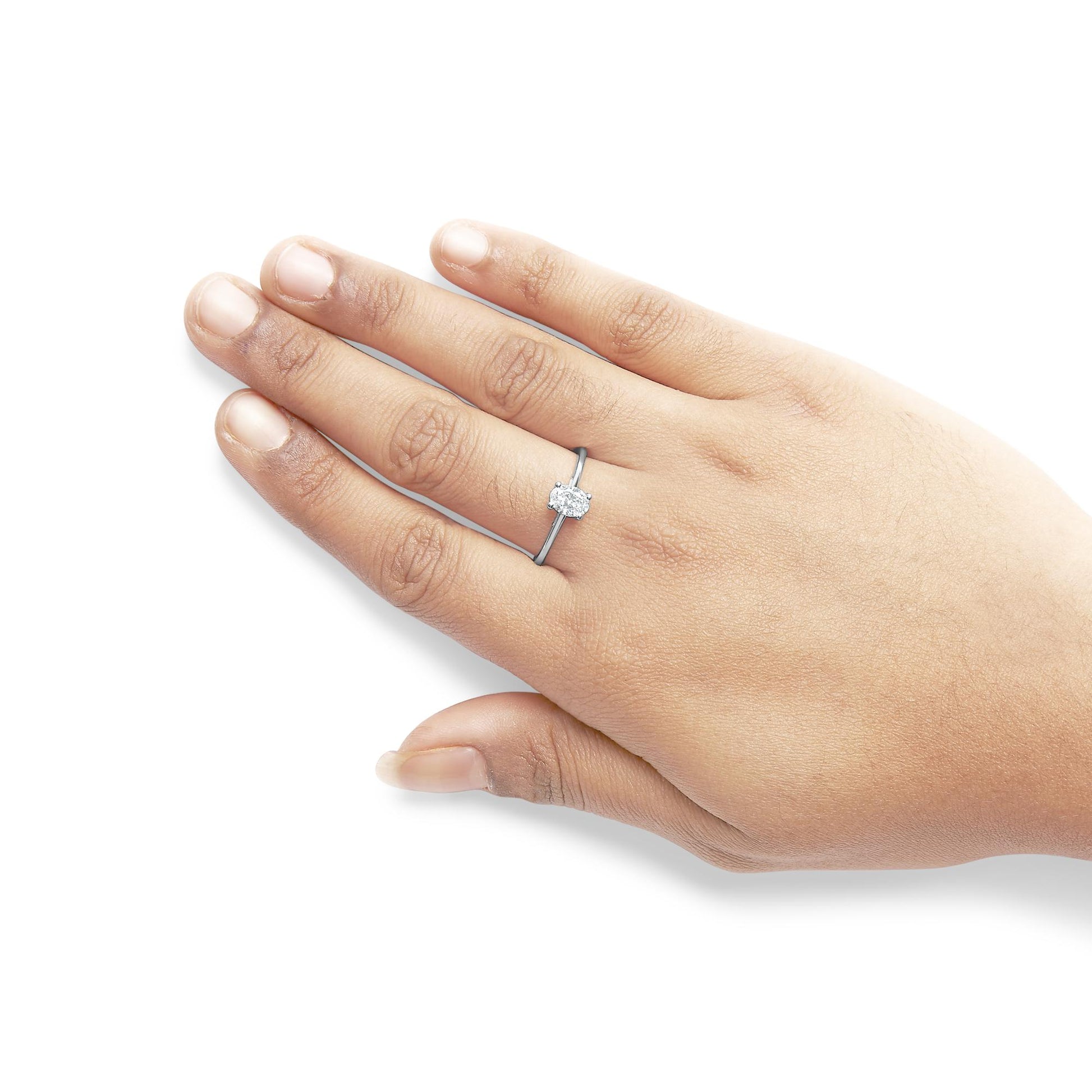White metal ring with a heart-shaped white gemstone in a 3-prong setting, shown on a model's hand from a top-down angle.