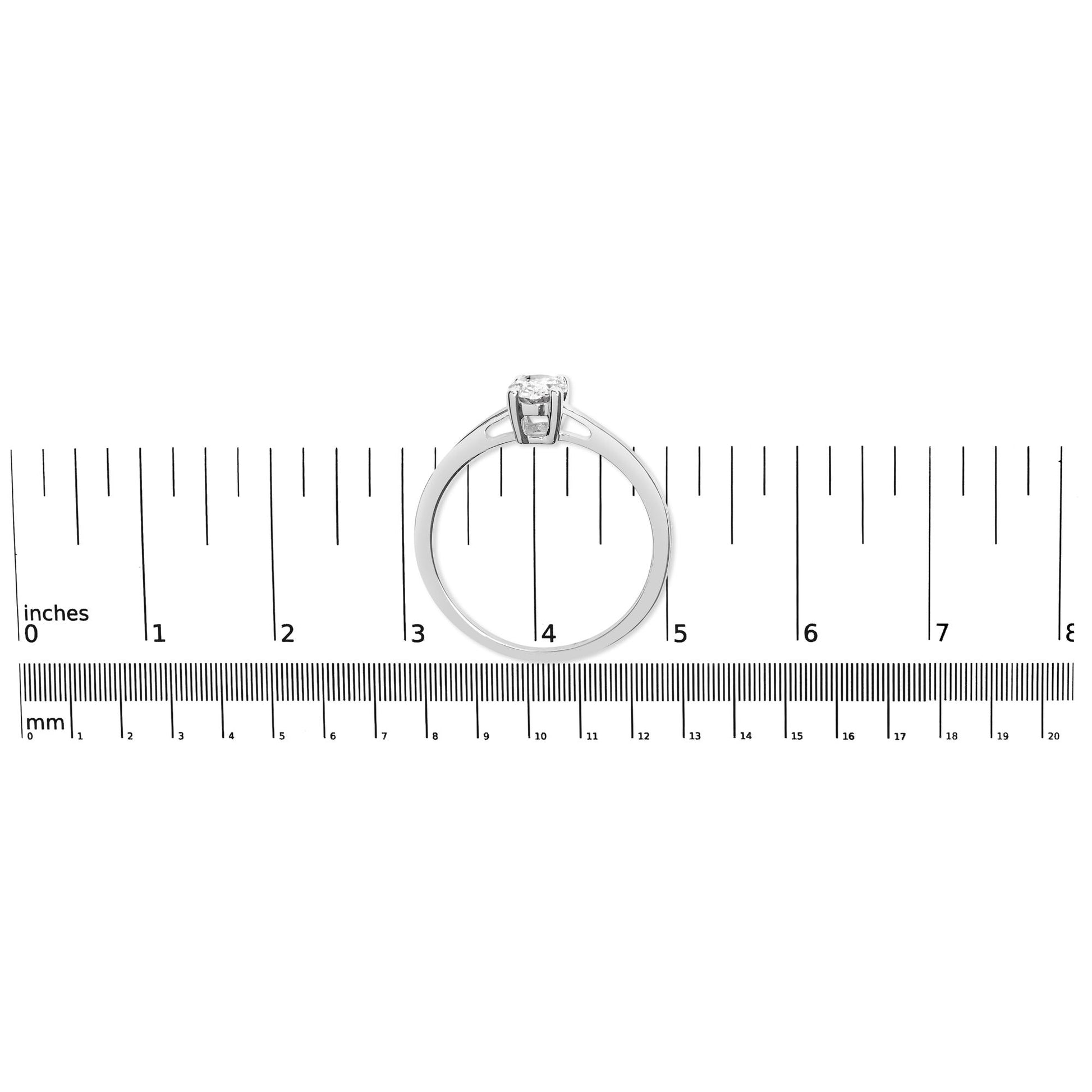 Top view of a white metal ring with an oval-shaped white gemstone in a four-prong setting, placed on a ruler for size reference.