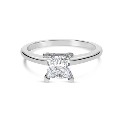 Front view of a white metal ring with a single princess shape white gemstone in a prong setting.