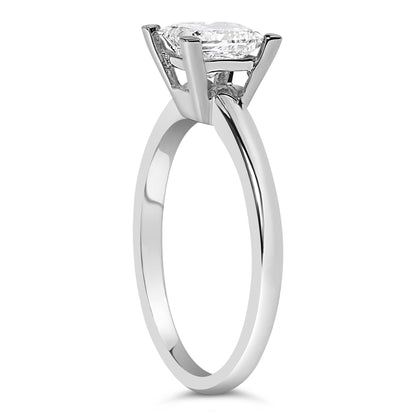 Side angle view of a white metal ring with a single white princess-shaped gemstone in prong setting.