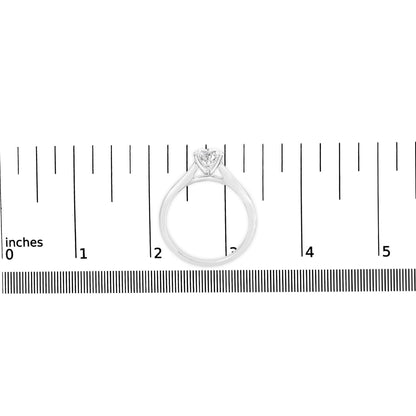 White metal ring with a round white gemstone in a four-prong setting, shown from the front on a ruler for size reference.