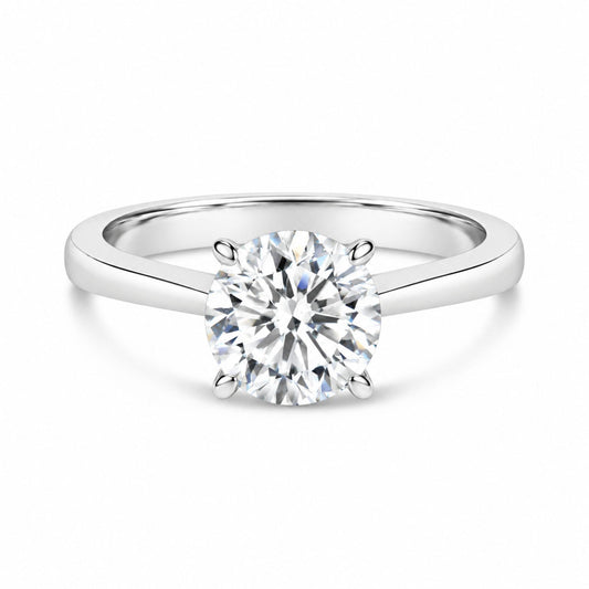 Close-up front angle of a white metal ring featuring a single round white gemstone set in a four-prong setting.
