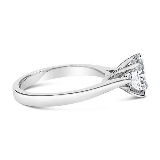 Close-up side angle of a white metal ring featuring a single round white gemstone in a four-prong setting.