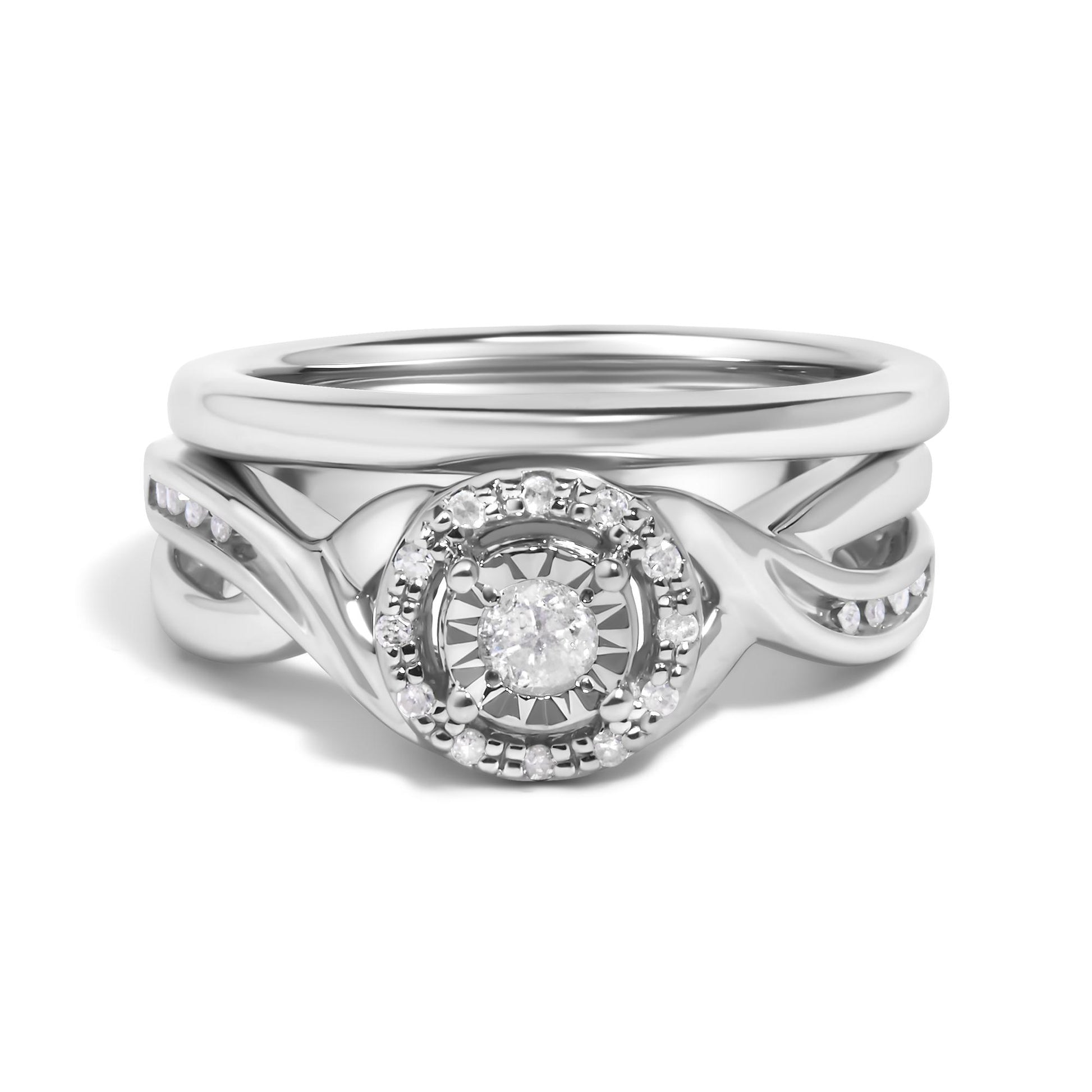 Close-up front view of a white metal ring set featuring a central round white gemstone surrounded by smaller round white gemstones in prong settings, with an intertwined band design accented by additional small round white gemstones.