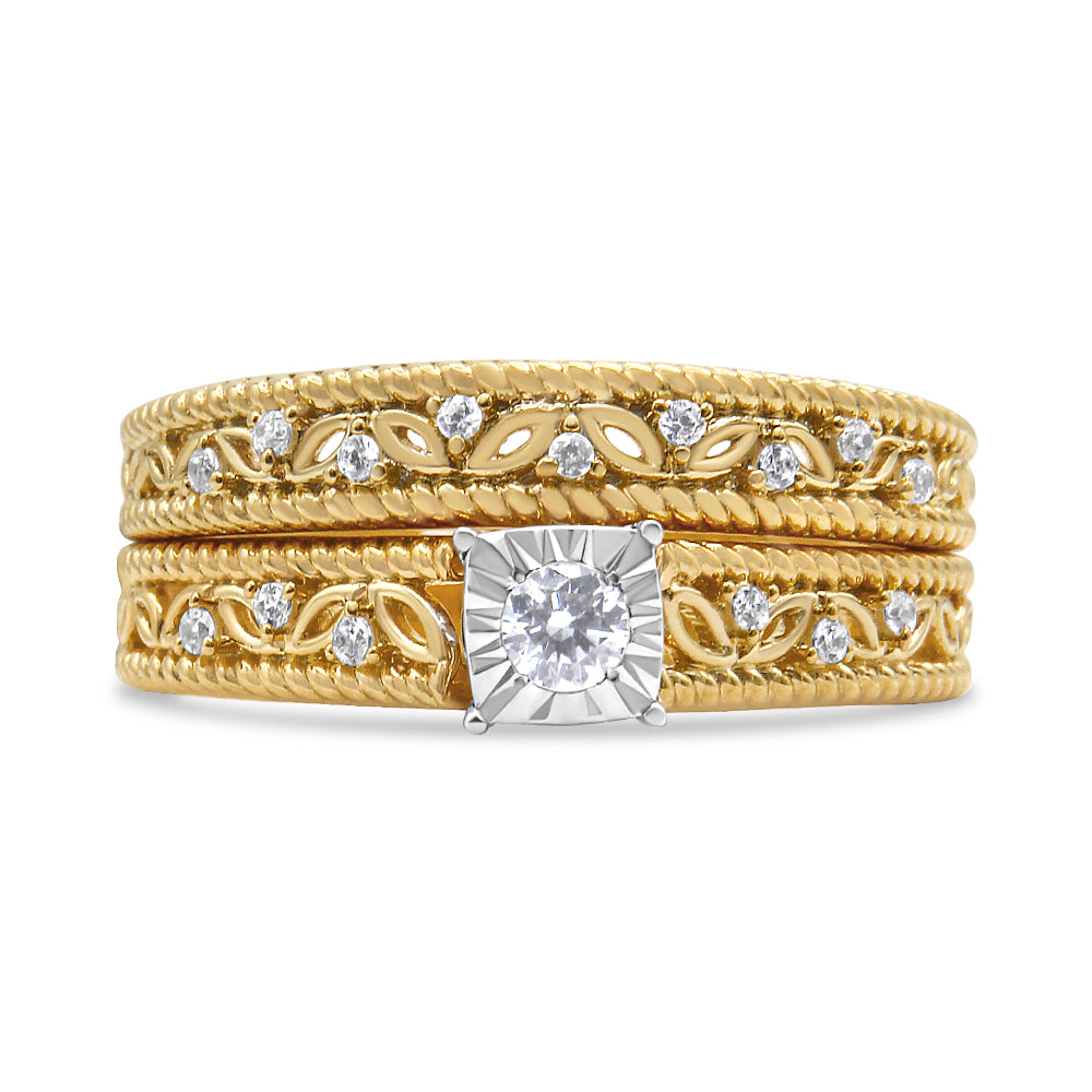 Close-up front view of a yellow metal ring with a central round white gemstone set in a prong setting on a square-shaped mount, flanked by intricate vine and leaf patterns accented with smaller round white gemstones in prong settings.