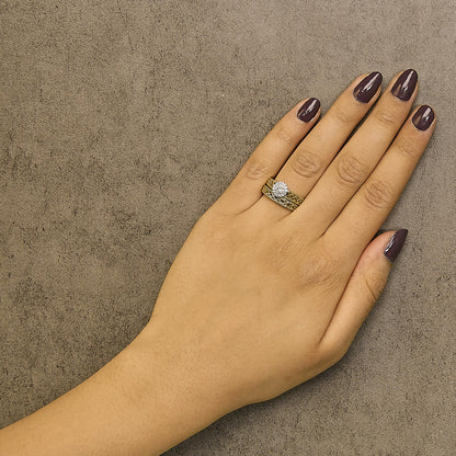 Top view of a yellow ring set on a model's finger featuring one larger round white gemstone in prong setting surrounded by smaller round white gemstones also in prong settings.