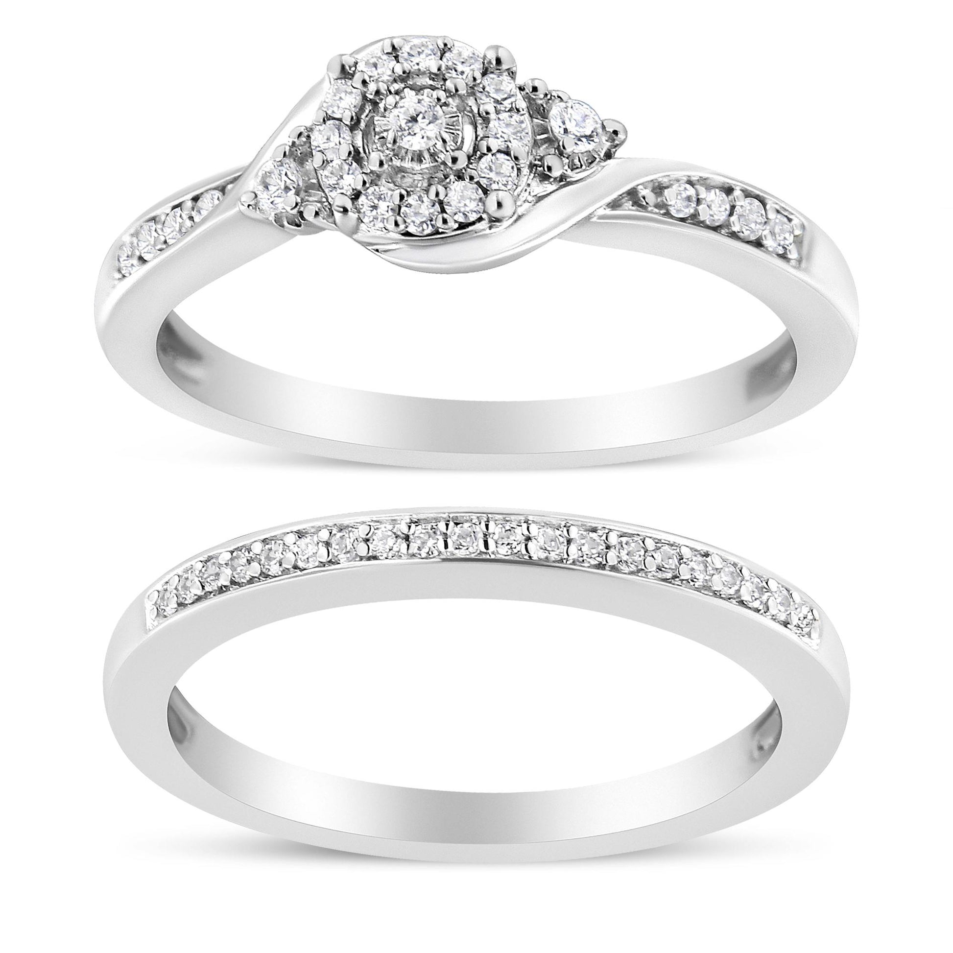 Top view of two white metal rings with round white gemstones in prong settings; the upper ring features a cluster center design and side gemstones, while the lower ring has a row of gemstones along the band.