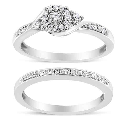 Top view of two white metal rings with round white gemstones in prong settings; the upper ring features a cluster center design and side gemstones, while the lower ring has a row of gemstones along the band.