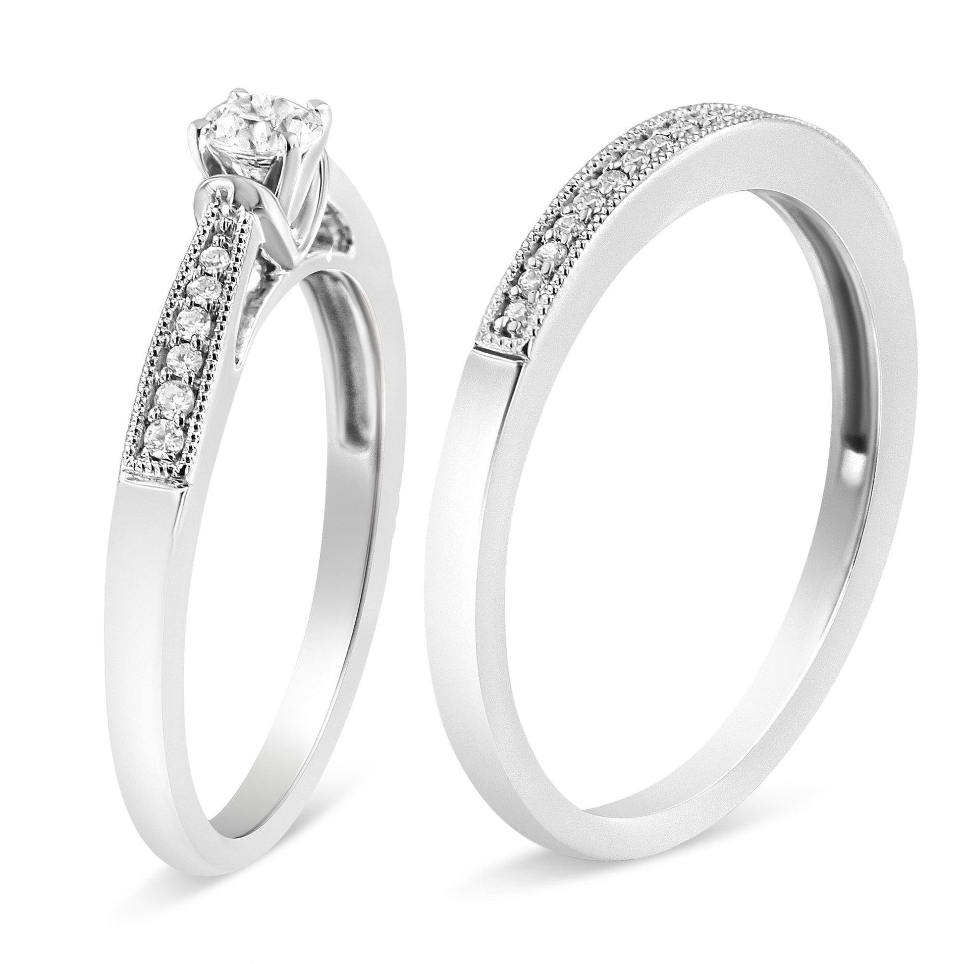 Two white metal rings shown in a close-up angled side view, each adorned with multiple small white gemstones on the bands, one featuring a single larger white gemstone in a four-prong setting.