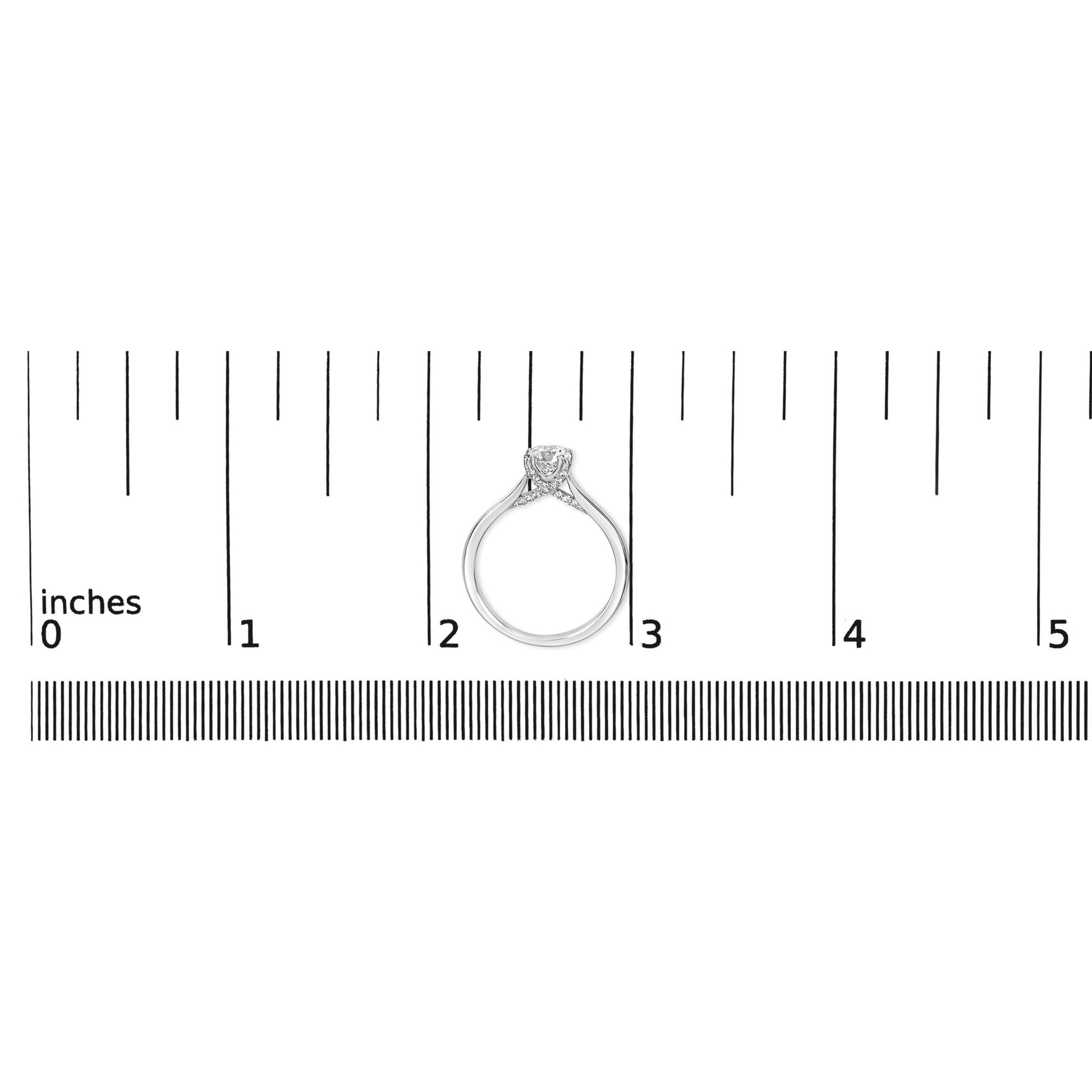 White metal ring with a single round white gemstone in a four-prong setting and multiple smaller round white gemstones in prong settings, shown from the side on a ruler for size reference.