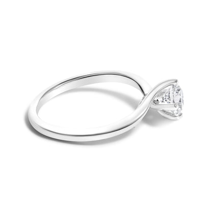 White metal ring with a round white gemstone in a four-prong setting, shot at a slight angle showing the band and setting side.